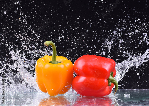 drops of water fall on the red and yellow pepper, splash