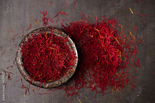 saffron spice threads and powder  in vintage iron dish © Elena Moiseeva