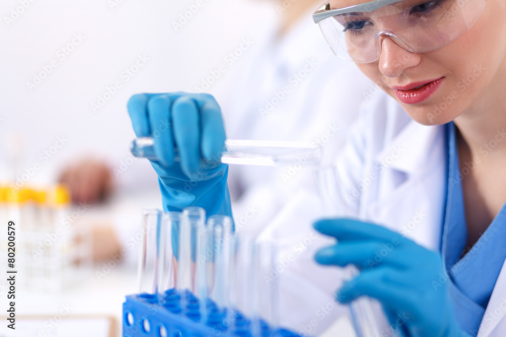 Fototapeta premium Woman researcher is surrounded by medical vials and flasks