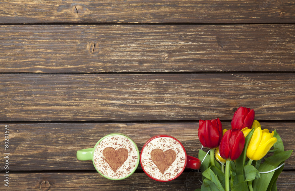two cappuccinos with heart shape and bouquet of tulips two cappuccinos with heart shape and bouquet of tulips