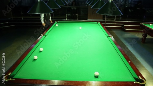 Player walk around green billiard table in dark club photo