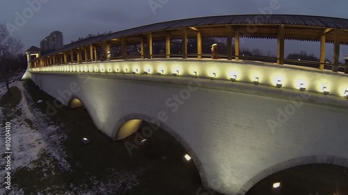 Tourists walk by Rostokinsky aqueduct with wooden roof photo