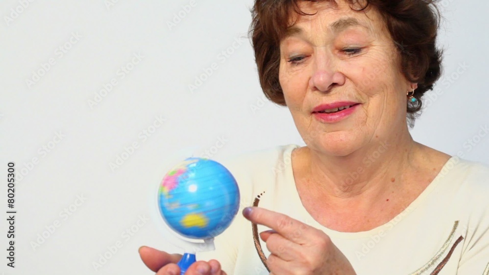 Senior woman holds earth miniature and spins it, closeup Senior woman holds earth miniature and spins it, closeup