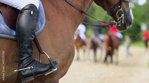 Horseman leg in boot at stirrup on chestnut horse, closeup photo