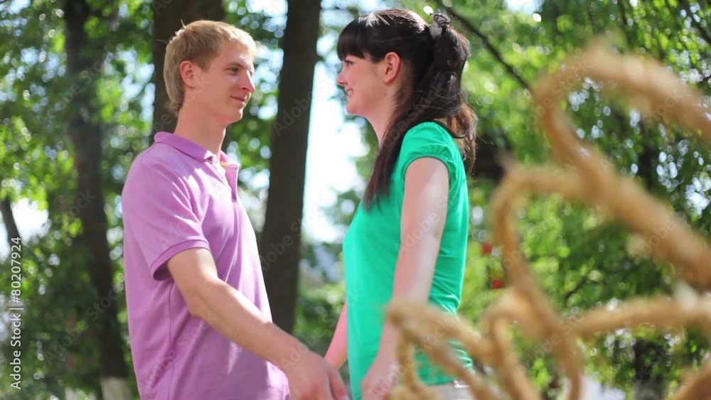 Couple smile and hold hands near braided fence