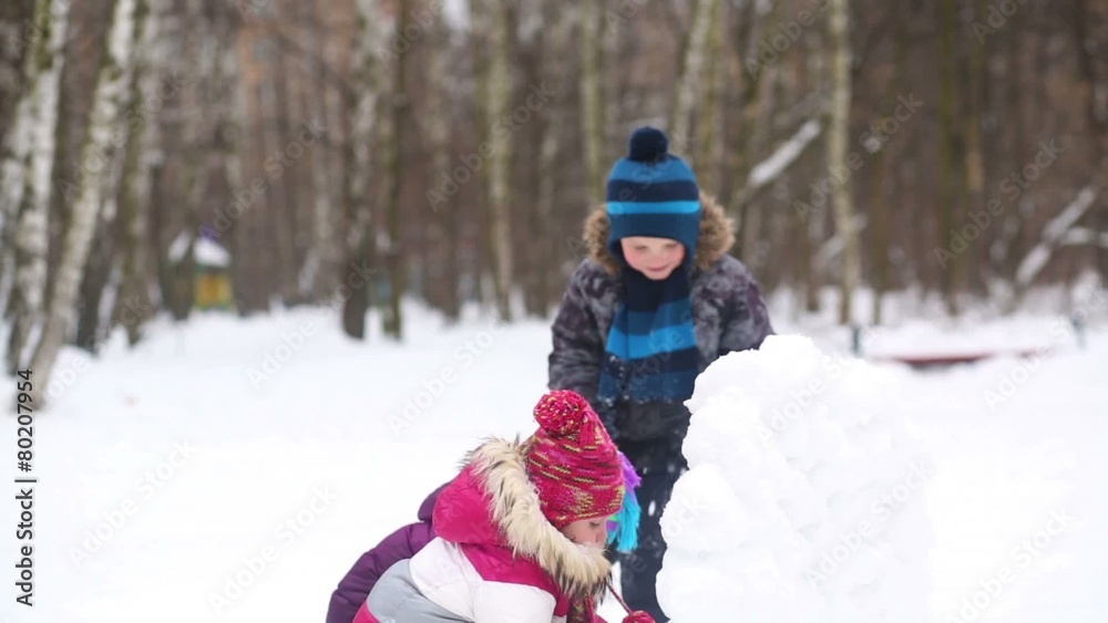 Three children throw snowballs from the snow wall guard Three children throw snowballs from the snow wall guard