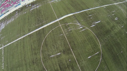 Field grass surface with snow on soccer stadium at winter day photo