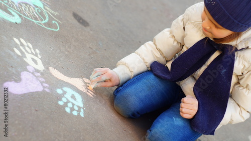 Girl drawing with colored chalk on the pavement