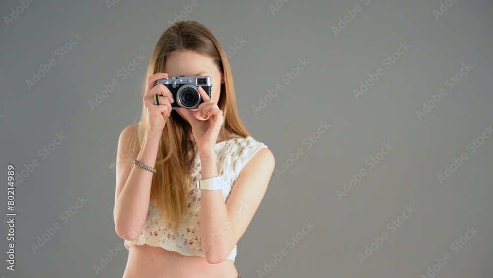 Woman with vintage camera filming against grey background. 