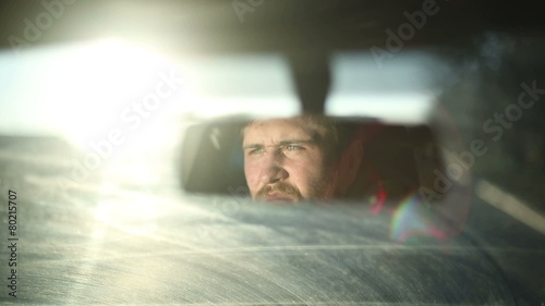 A man drives a car. Reflection in the mirror. Sunset