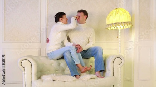 Couple flirting with each other sitting on the sofa barefoot