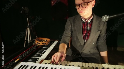 Handsome man in glasses plays keyboard in night club with smoke