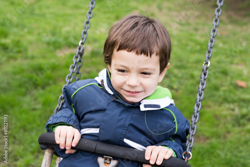 kid swinging happy in the park on a cold day