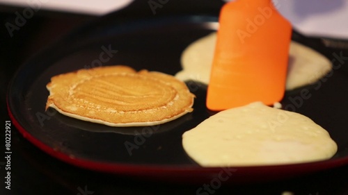 Three little fritters are fried on pan and turn over by turner photo