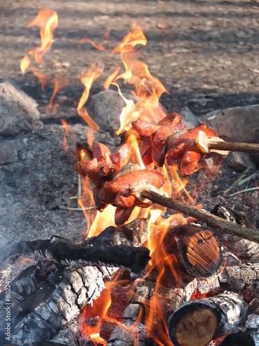 Roast sausages over a fire in the wild.