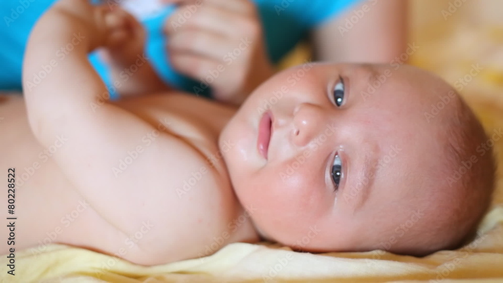 small child lying on back both stirring handles and hands of mother behind