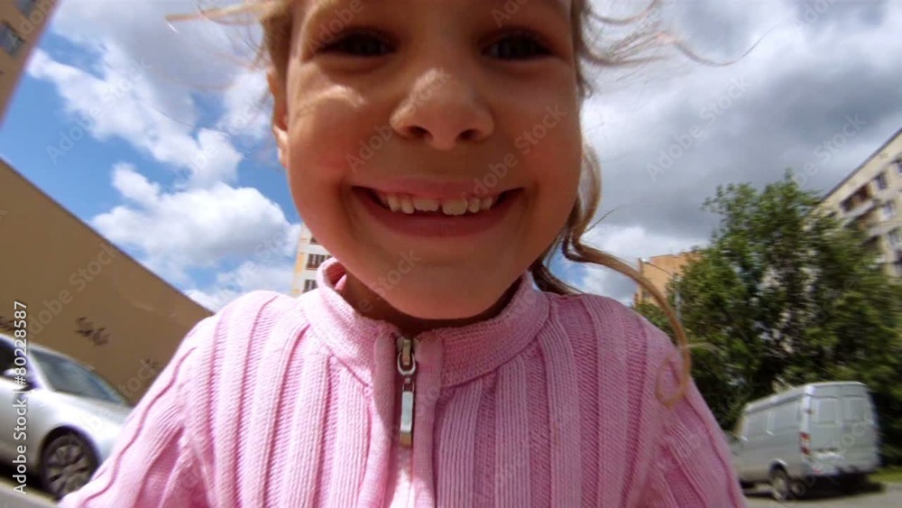 Beautiful girl goes on scooter on road in house yard