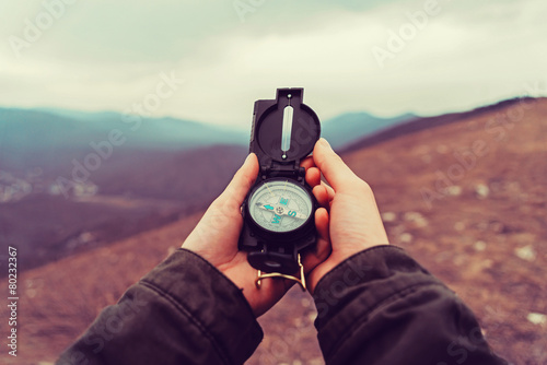Foto Hiker woman with a compass in the mountains