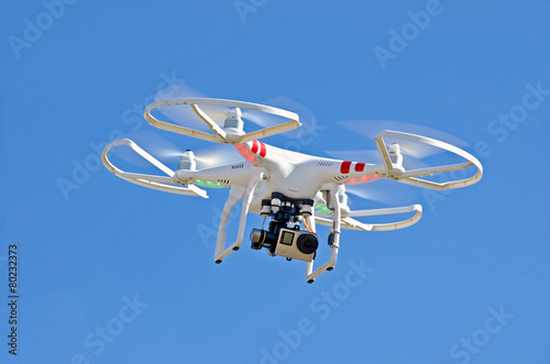 white drone hovering in blue sky