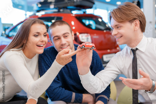 Salesman demonstrates toy car model to customers