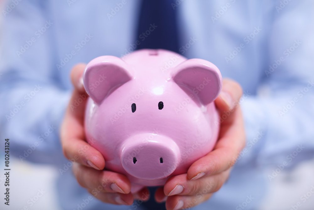 Businessman holding piggy box ,standing in office Businessman holding piggy box ,standing in office