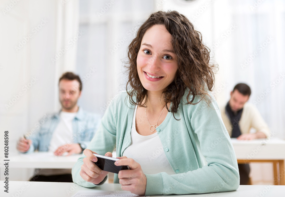 Young attractive student using smartphone during classes Young attractive student using smartphone during classes