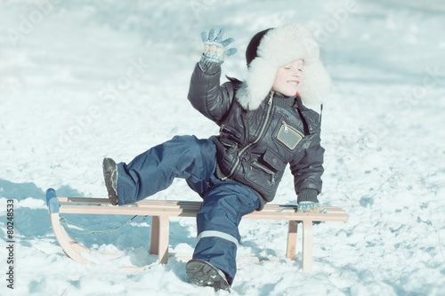 Canvastavla boy on sled with close eyes enjoying the winter sun