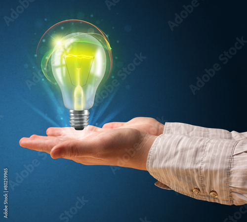 Glowing lightbulb in the hand of a woman