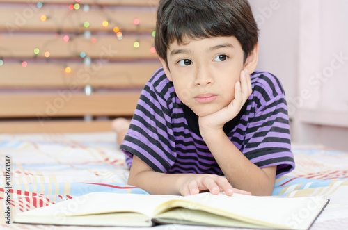 Little boy thinking while writing in the room