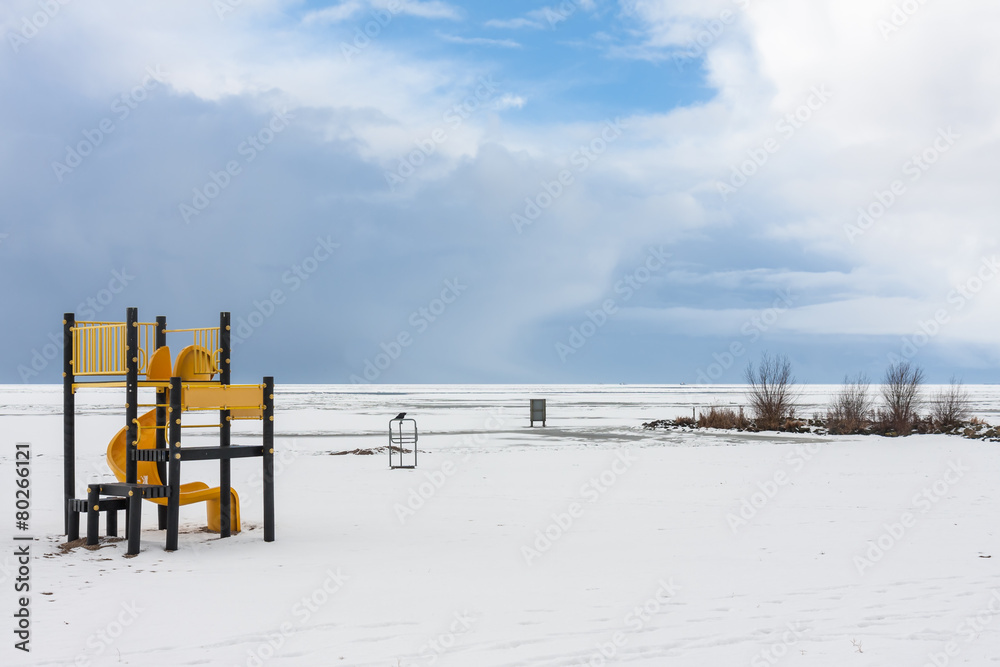 Snowy beach near a frozen sea with a playground for children Snowy beach near a frozen sea with a playground for children