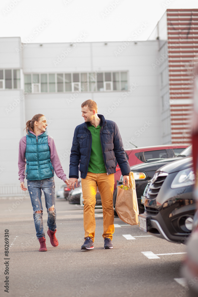 Couple walking after shopping near cars Couple walking after shopping near cars