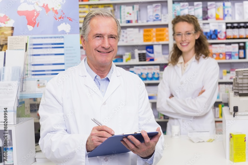 Senior pharmacist writing on clipboard