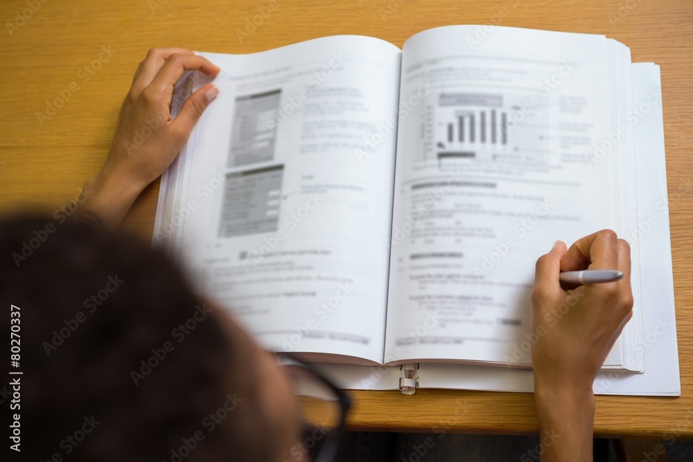 Fototapeta premium Student sitting in library writing