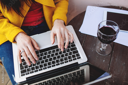 Woman with red wine tablet and laptop in street cafe