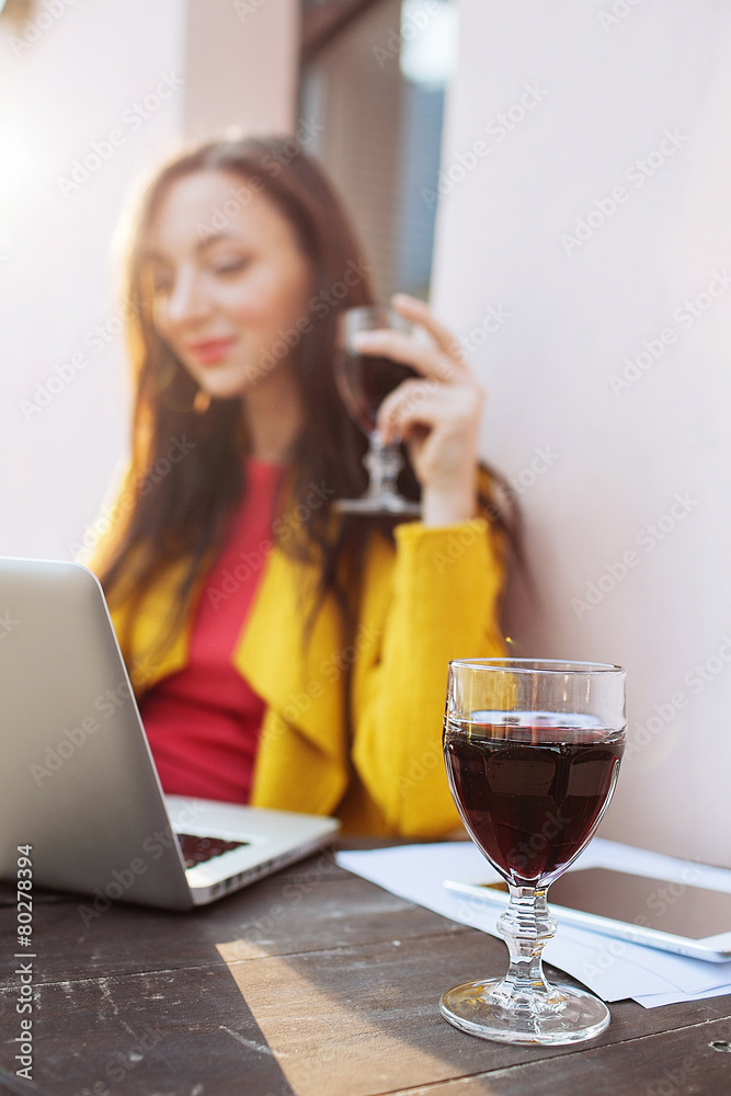 Woman with red wine tablet and laptop in street cafe Woman with red wine tablet and laptop in street cafe