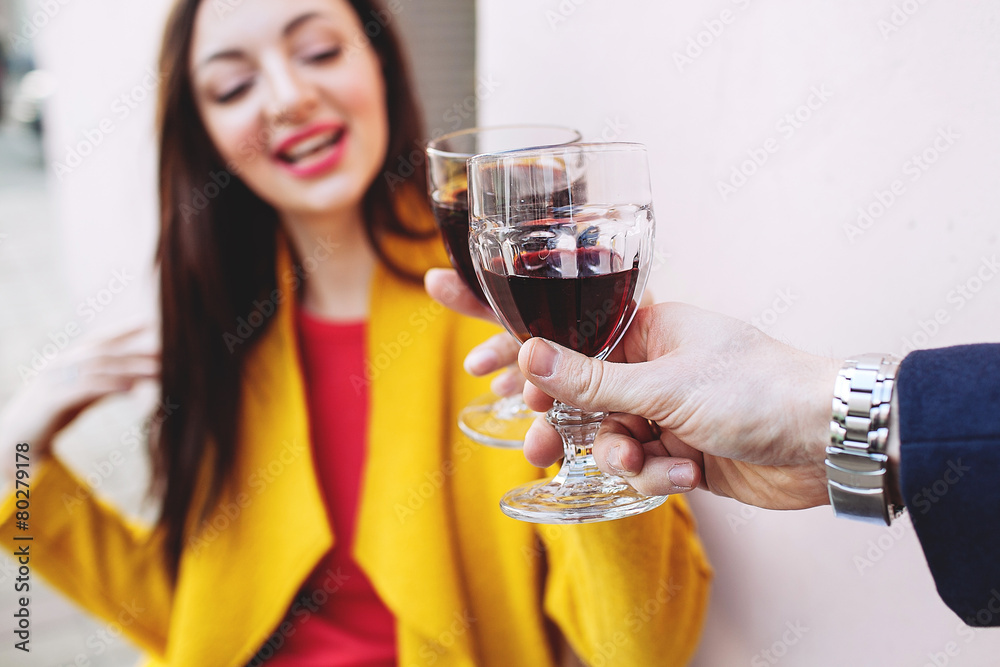 Woman clinking red wine glass with man outdoors