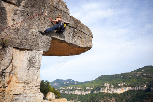 Young woman climbing a challenging route on a cliff 