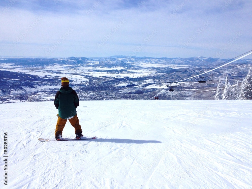 Snowboarder on top of a mountain enjoying the view