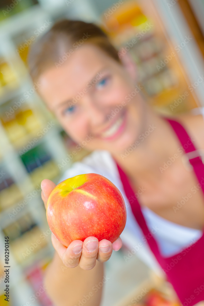 Shop assistant holding up an apple Shop assistant holding up an apple
