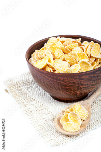 Cornflakes in a wooden bowl on white background.