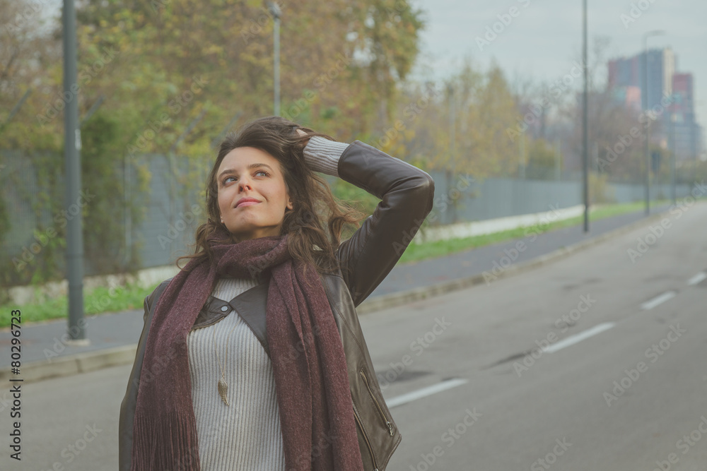 Naklejka premium Beautiful young brunette posing in the city streets