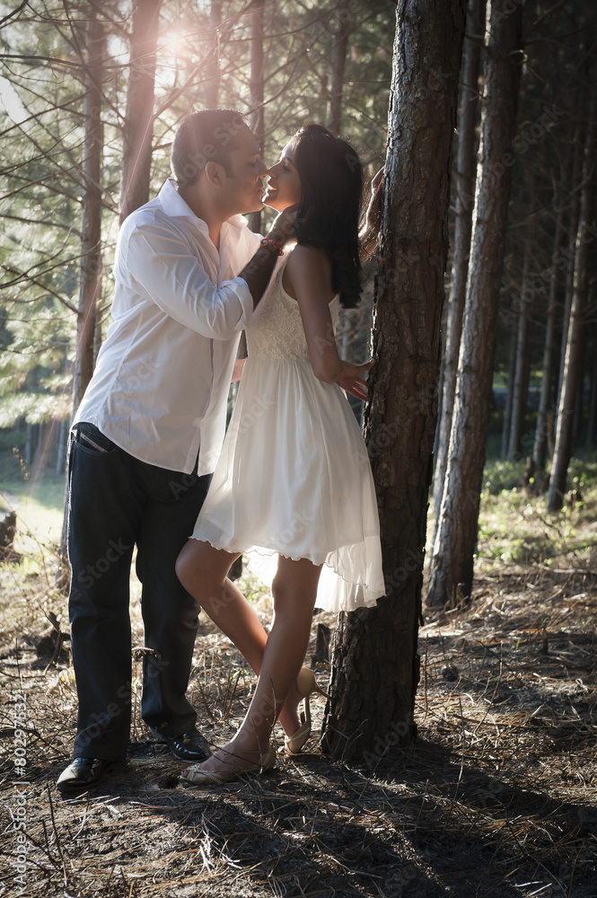 Young happy Indian in love couple flirting in forest of trees