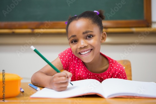 Obraz na plátně Cute pupils writing at desk in classroom