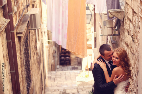 groom and bride on a narrow street © hreniuca