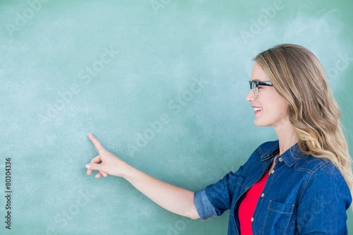 Smiling geeky teacher pointing the blackboard