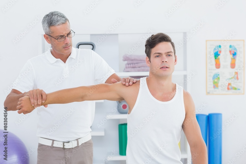 Obraz premium Doctor stretching a young man arm