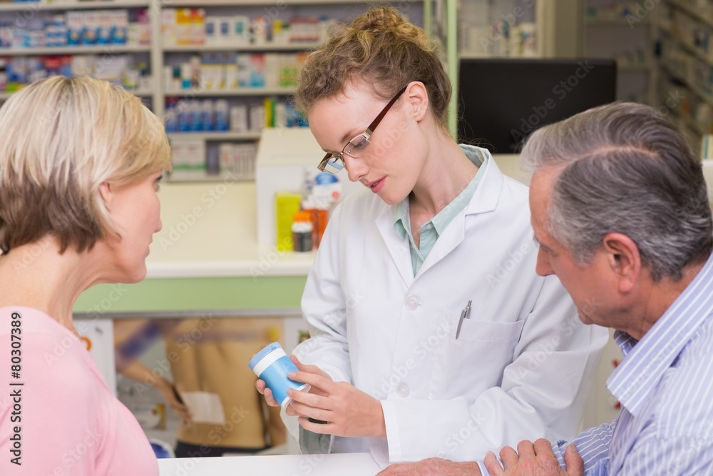 Pharmacist holding a bottle of drugs talking to customer Pharmacist holding a bottle of drugs talking to customer