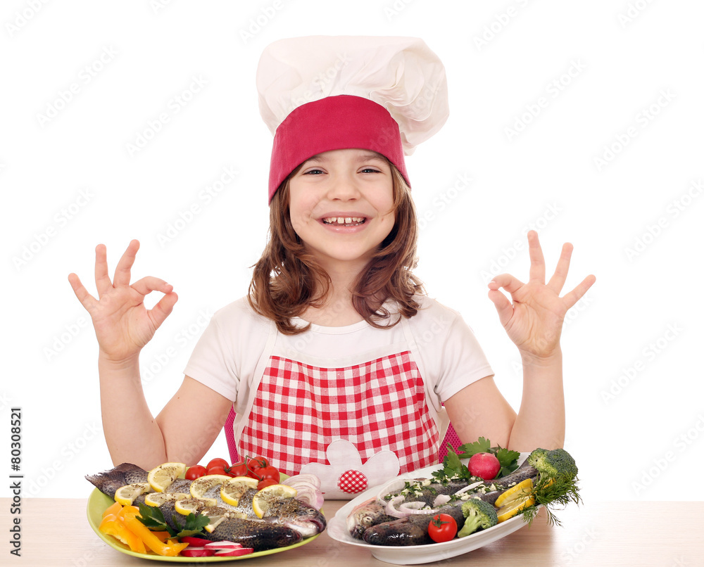 happy little girl cook with fishes and ok hand sign happy little girl cook with fishes and ok hand sign