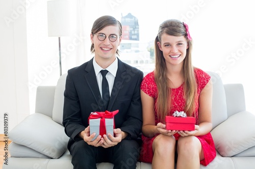 Cute geeky couple smiling and holding gift