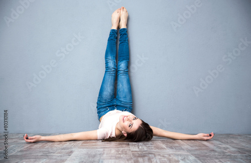 Smiling attractive woman lying on the floor with legs raised up photo